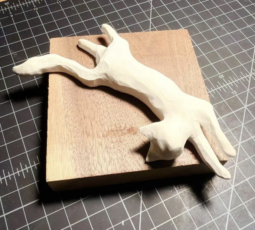 Clay cat leaping across a wooden base