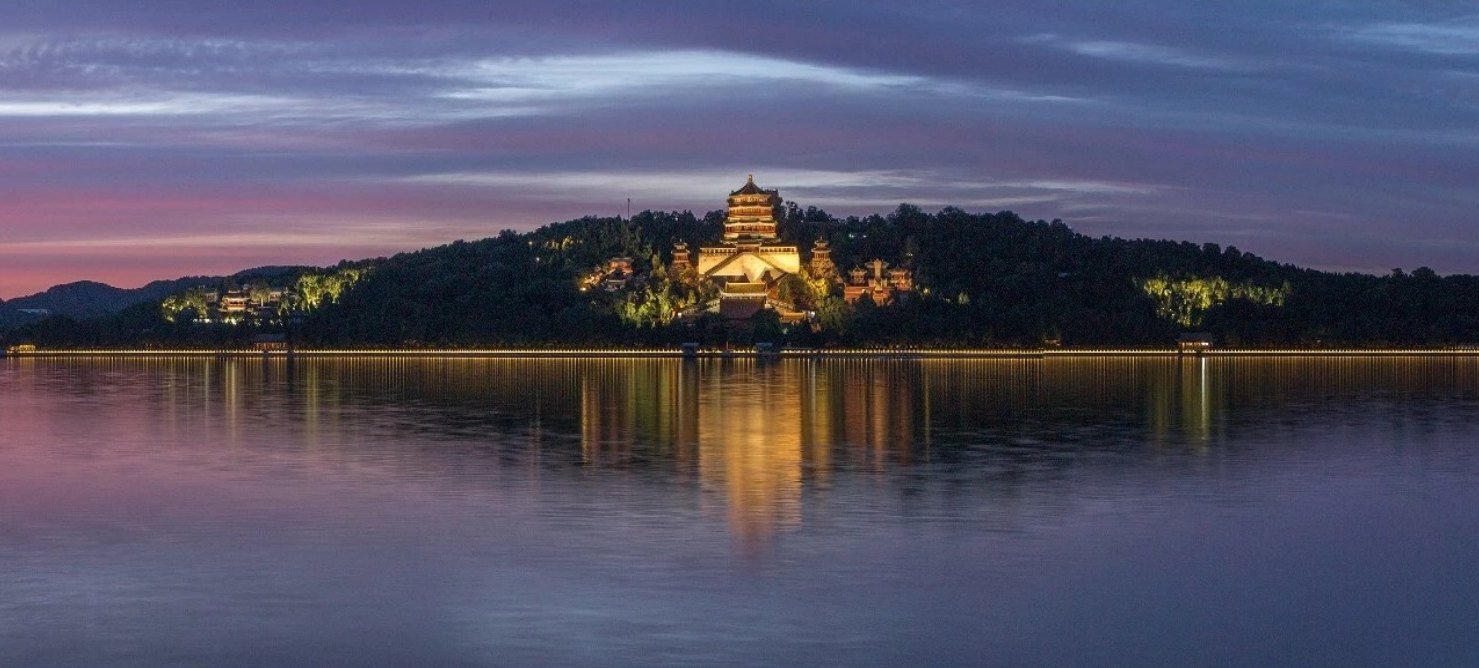 Longevity Hill and its pagoda lit at dusk, reflected across Kunming Lake