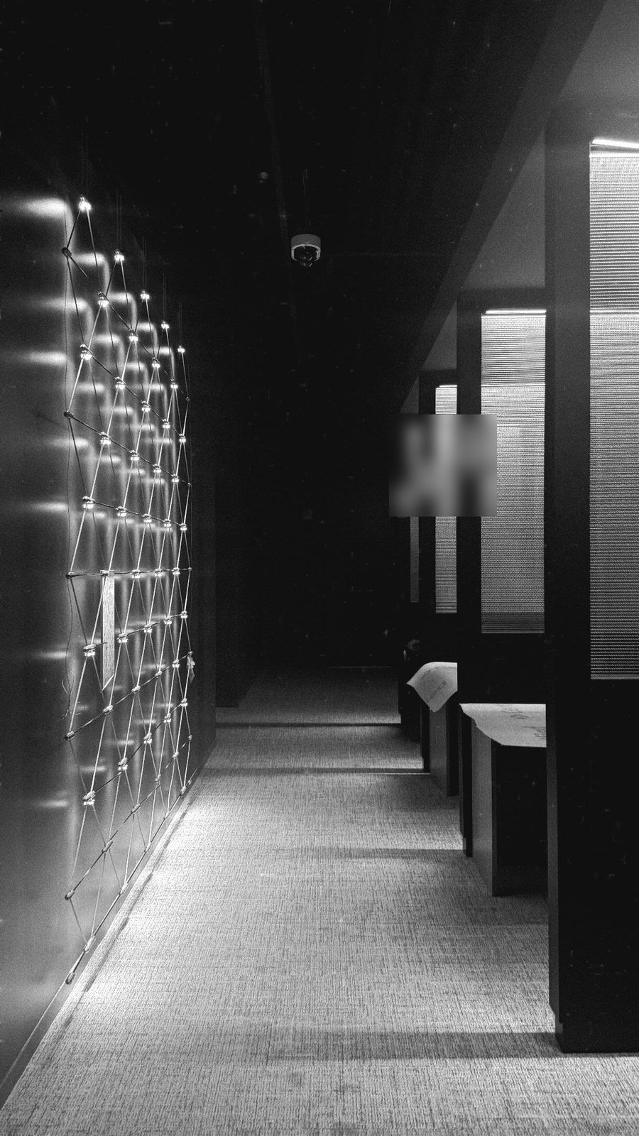 Dark corridor with a wall of suspended point-source lights on a cable net